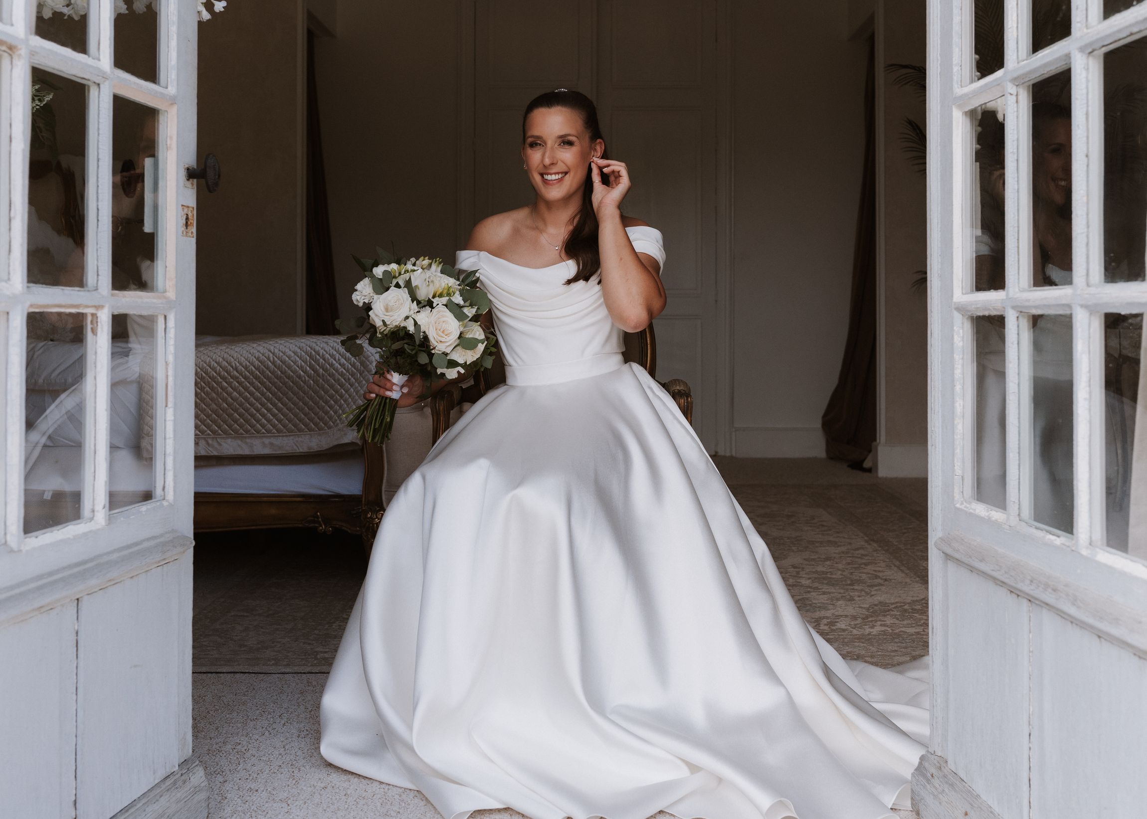 A bride takes a quiet moment of reflection before walking down the aisle, framed by the soft glow of a French château interior.