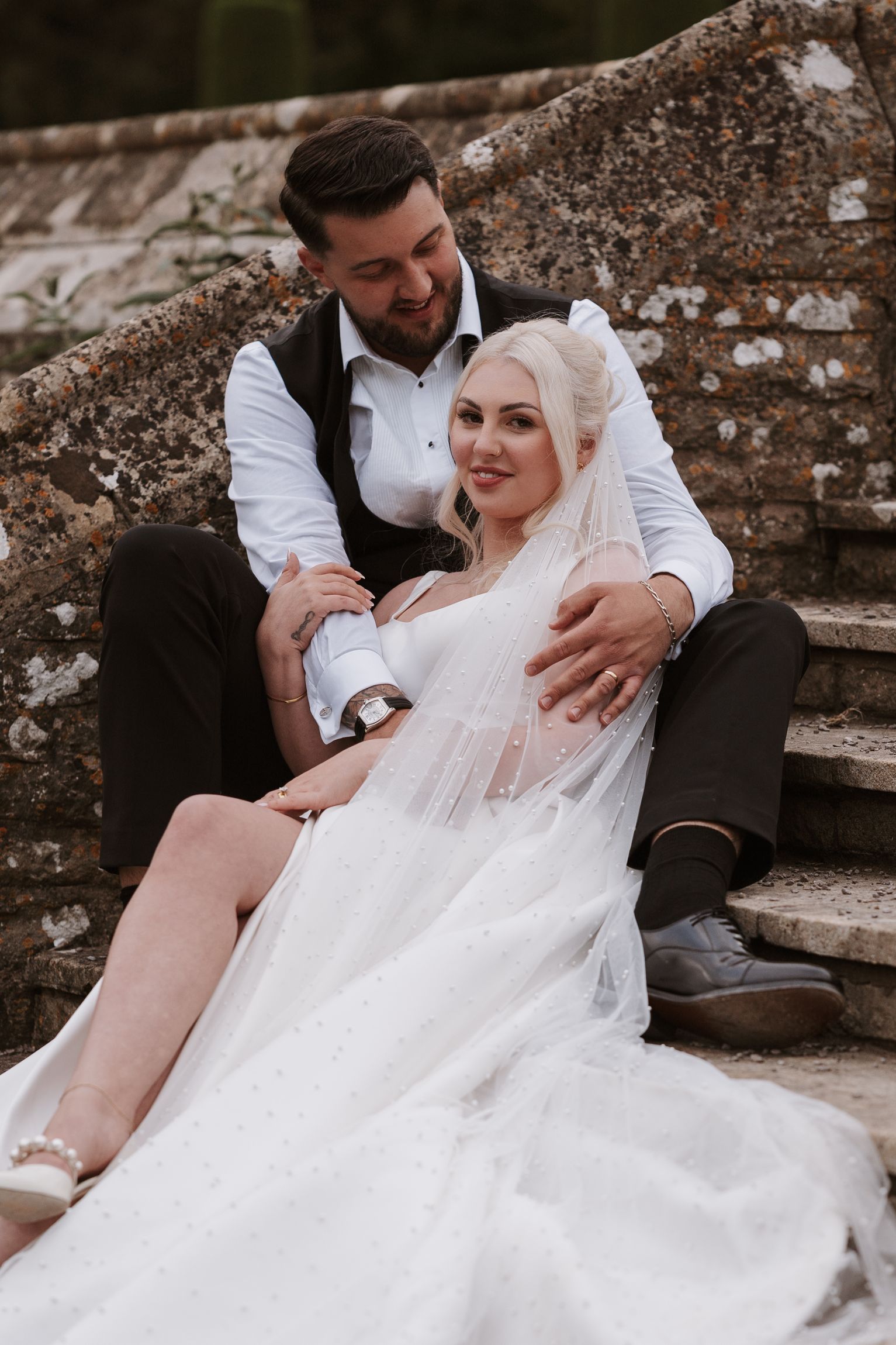 bride and groom sitting on steps posed, photographed by Sawyer & Co
