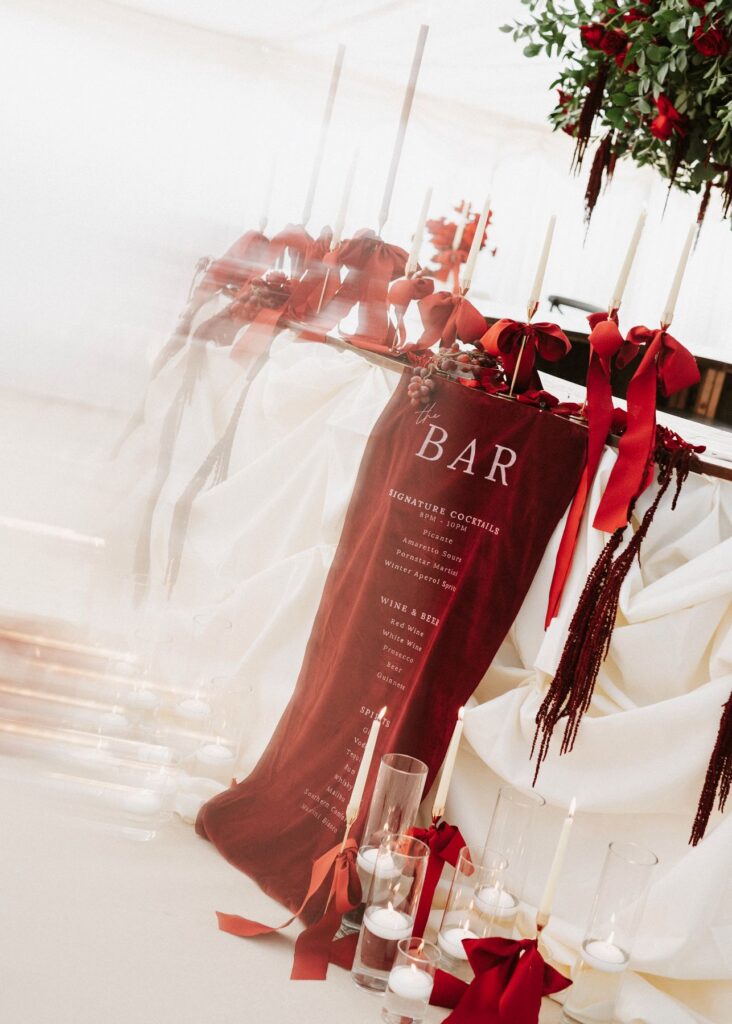 Red bar details for a winter wedding, adorned with red roses and green foliage by Eve Designs